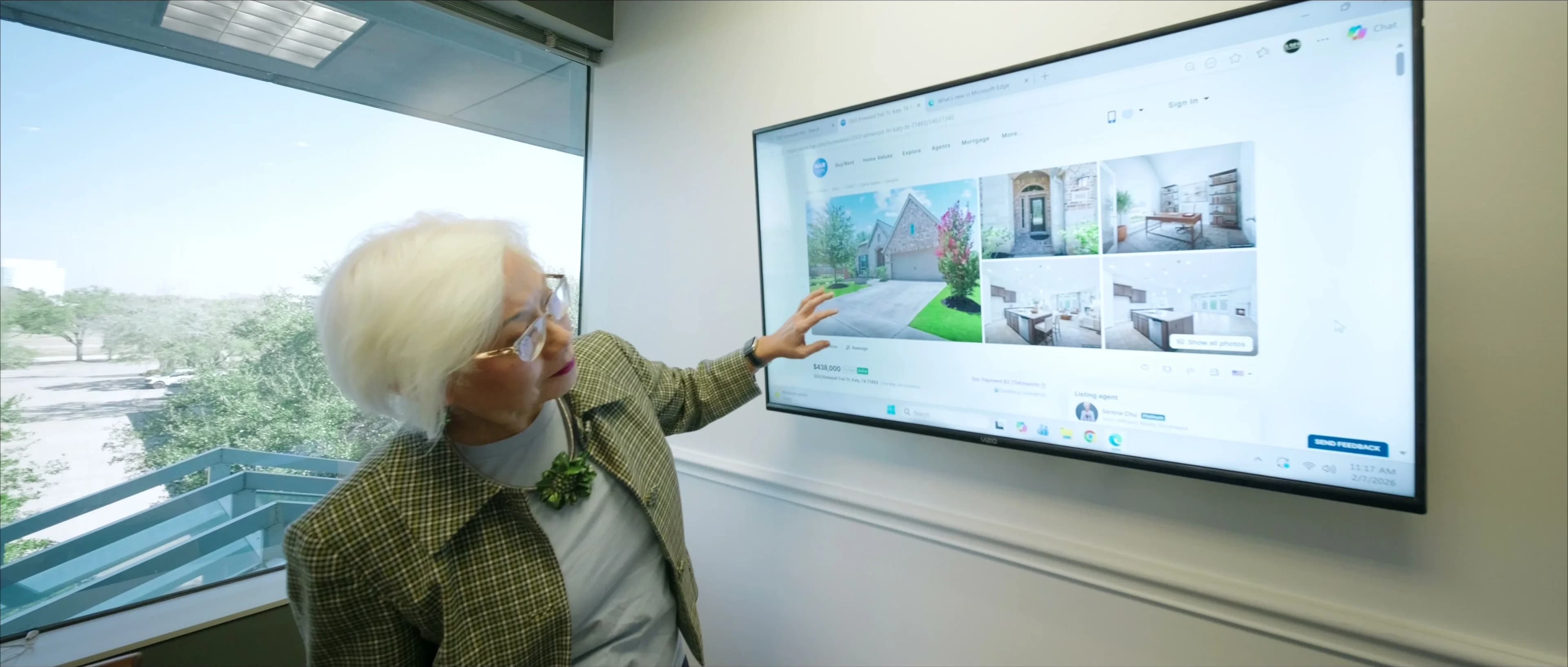 Serena Chu pointing at a home listing on an office monitor