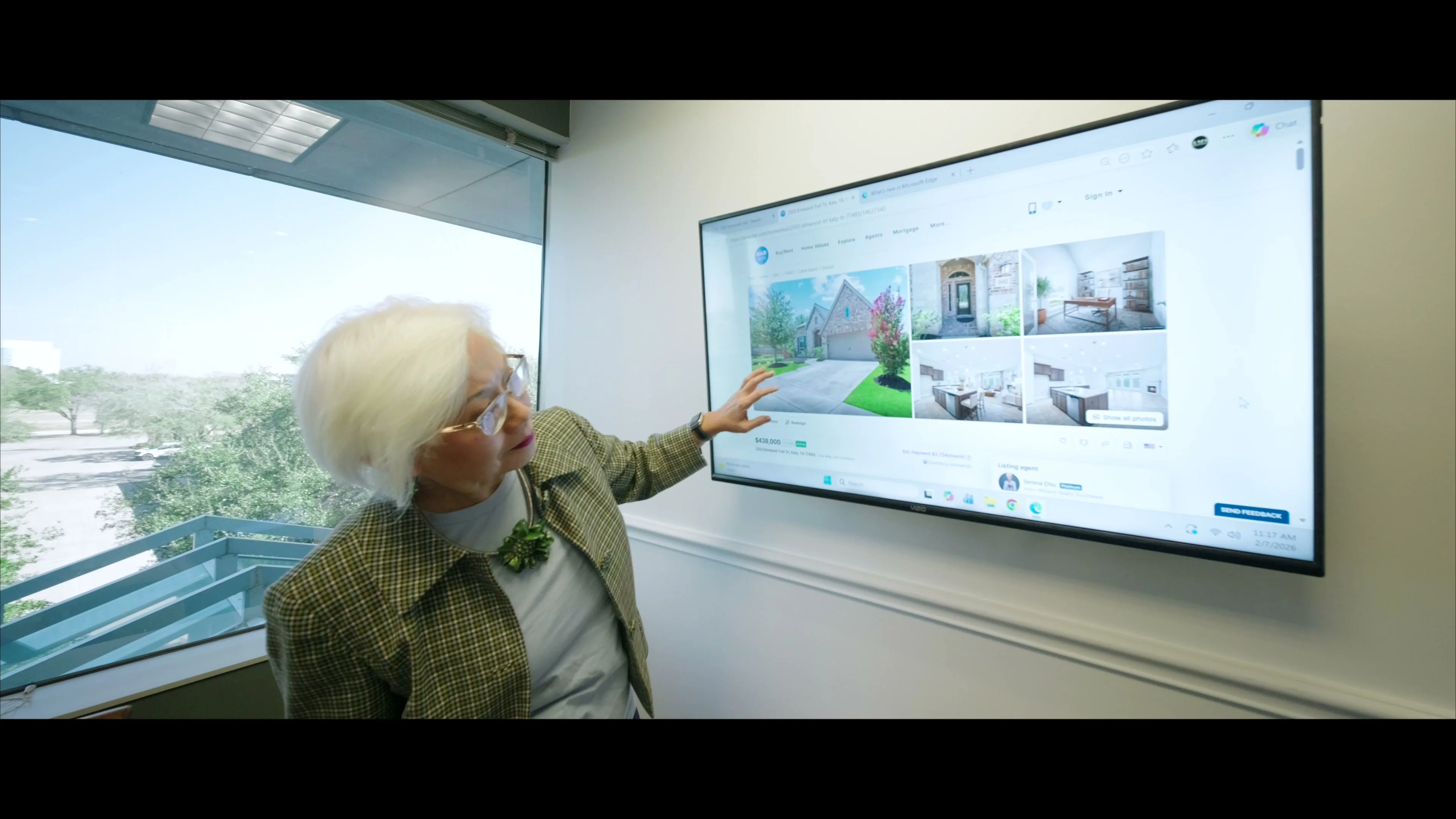 Serena Chu pointing at a home listing on an office monitor